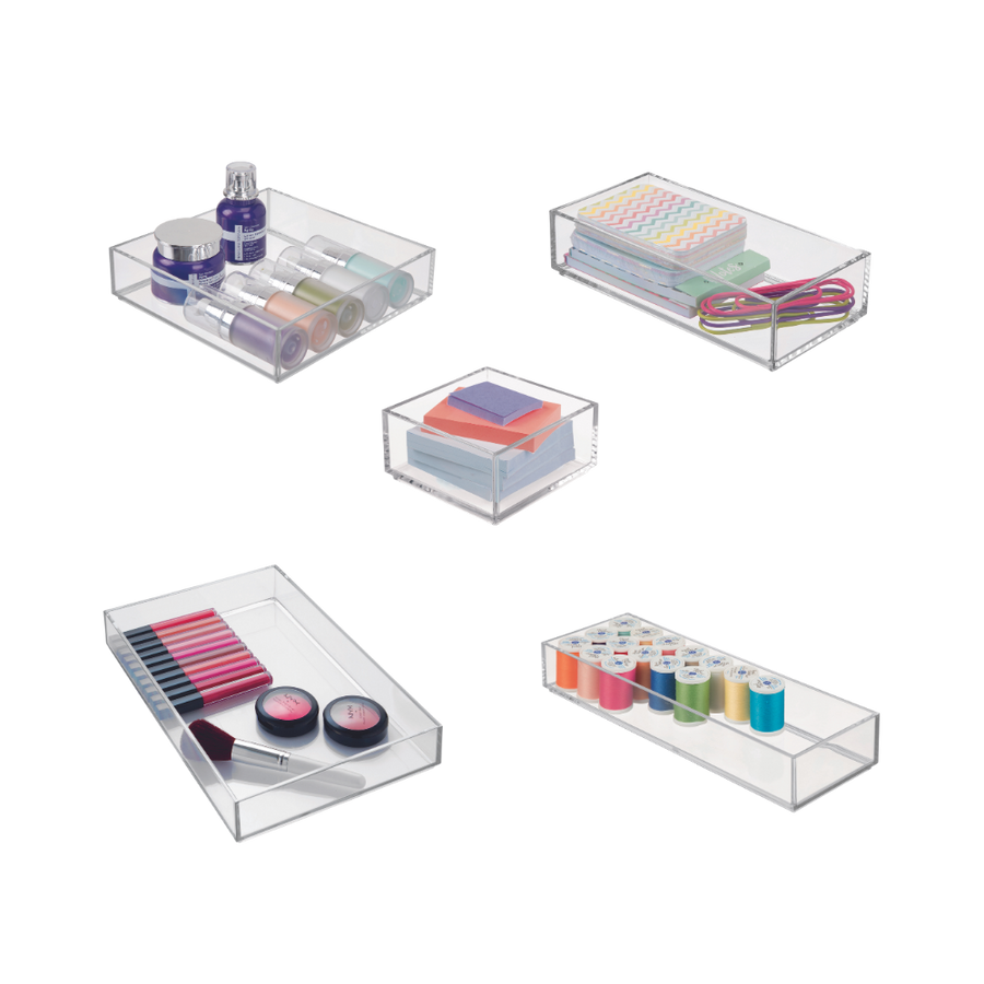 Transparente Aufbewahrungsboxen mit Kosmetik, Stiften, Garn und Gummibändern im Raum.