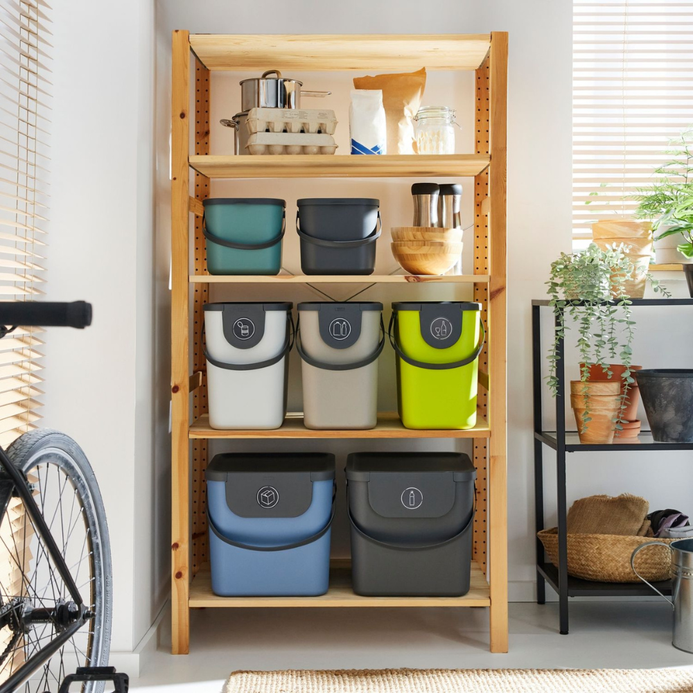 Regaleinheit mit Plastikbehältern, daneben Pflanzen und Fahrrad.