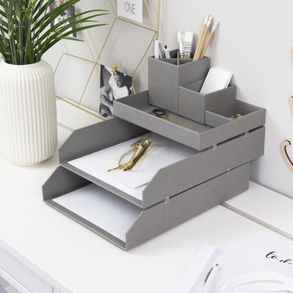 Die Bigso HAKAN Dokumentenablage Set 2 Stk. in Grau (A4 Format) ordnet Papiere, Schere und Stifte auf einem weißen Schreibtisch neben einer gerippten weißen Vase mit einer grünen Pflanze und einem goldenen Drahtfotorahmen im Hintergrund.