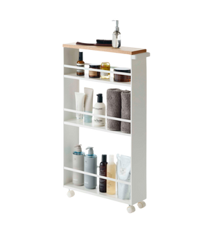 Regal auf Rollen mit Pflegeprodukten und Handtüchern, drei Ebenen mit weißem Rahmen und Holzplatte.