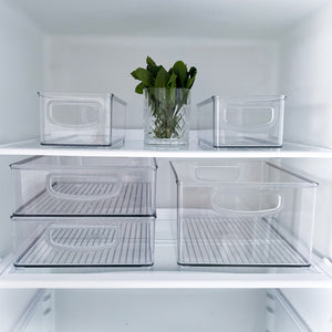 In einem aufgeräumten Kühlregal steht das iDesign Kühlschrank-Set MINI (5-teilig): fünf stapelbare Behälter, alle leer bis auf ein zentrales Glas mit frischen grünen Kräutern.