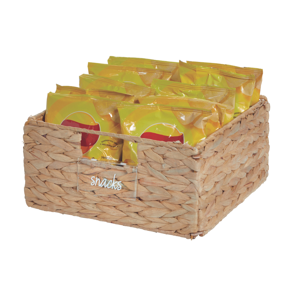 Der iDesign HOME EDIT Etikettenhalter KLAR (Set 3 Stk.) ist ein rechteckiger geflochtener Korb mit der Aufschrift "Snacks", in dem mehrere gelbe Snack-Tüten übersichtlich angeordnet sind. Sein Naturfaser-Look verleiht ihm einen strukturierten Stil.